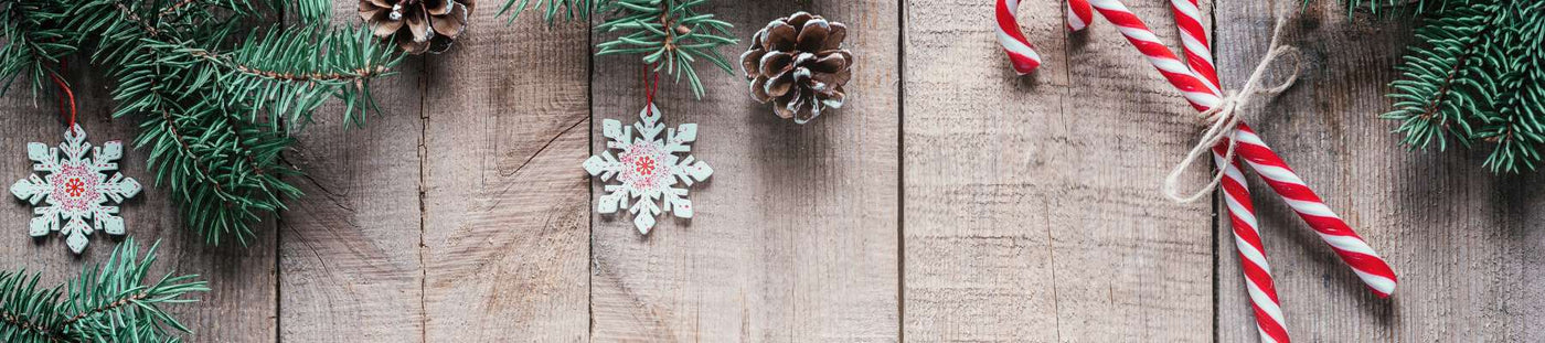 Decorative Christmas elements on a wooden surface including pine cones, snowflakes, and candy canes.