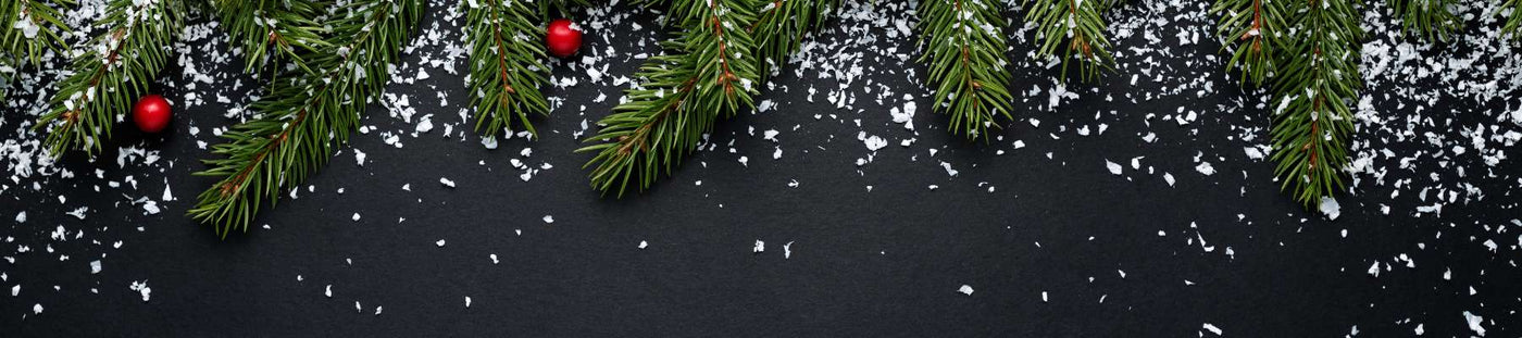Decorative arrangement of pine branches and red berries on a black background with snowflake confetti.
