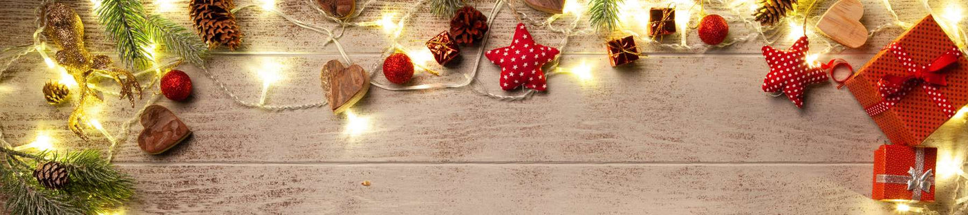 Decorative Christmas scene with lights, presents, and ornaments on a wooden surface.