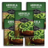 Multiple packages of Survival Garden Seeds Arugula with images of arugula in wooden bowls.