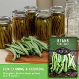Jars of canned green beans on a table with a package of Survival Garden Seeds beans.
