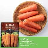 A seed packet for Survival Garden Seeds Carrot Chantenay Royal is shown next to a round woven basket filled with fresh orange carrots on a white background, with a green text banner at the bottom describing the carrots.