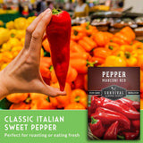 Hand holding a red sweet pepper with a 'Survival Garden Seeds' package in the background