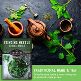 Herbal tea set with a package of Stinging Nettle seeds on a dark surface.