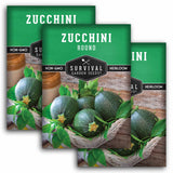 Three packages of Survival Garden Seeds Zucchini with green zucchinis and leaves on a wooden background.